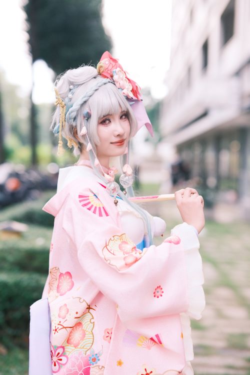 Free Young woman in a vibrant kimono posing outdoors with a fan. Stock Photo