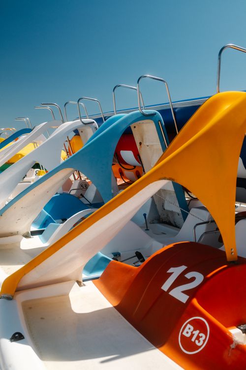 Free Vibrant pedal boats with numbers lined up under a clear blue sky, suggesting summer and leisure. Stock Photo
