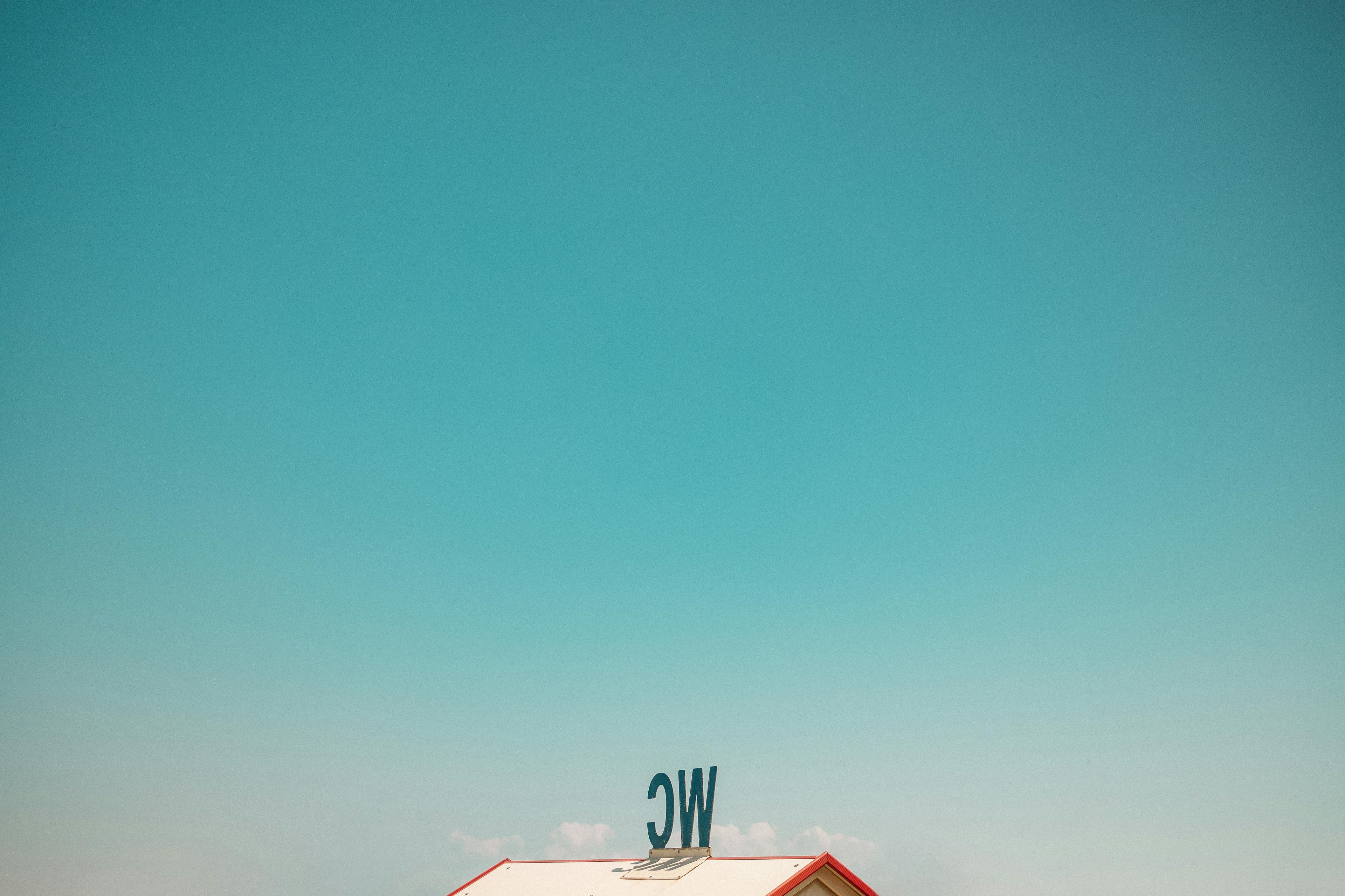 Gratis Immagine minimalista che mostra il tetto di un edificio sotto un cielo azzurro e limpido, con le lettere "WC" visibili. Foto a disposizione