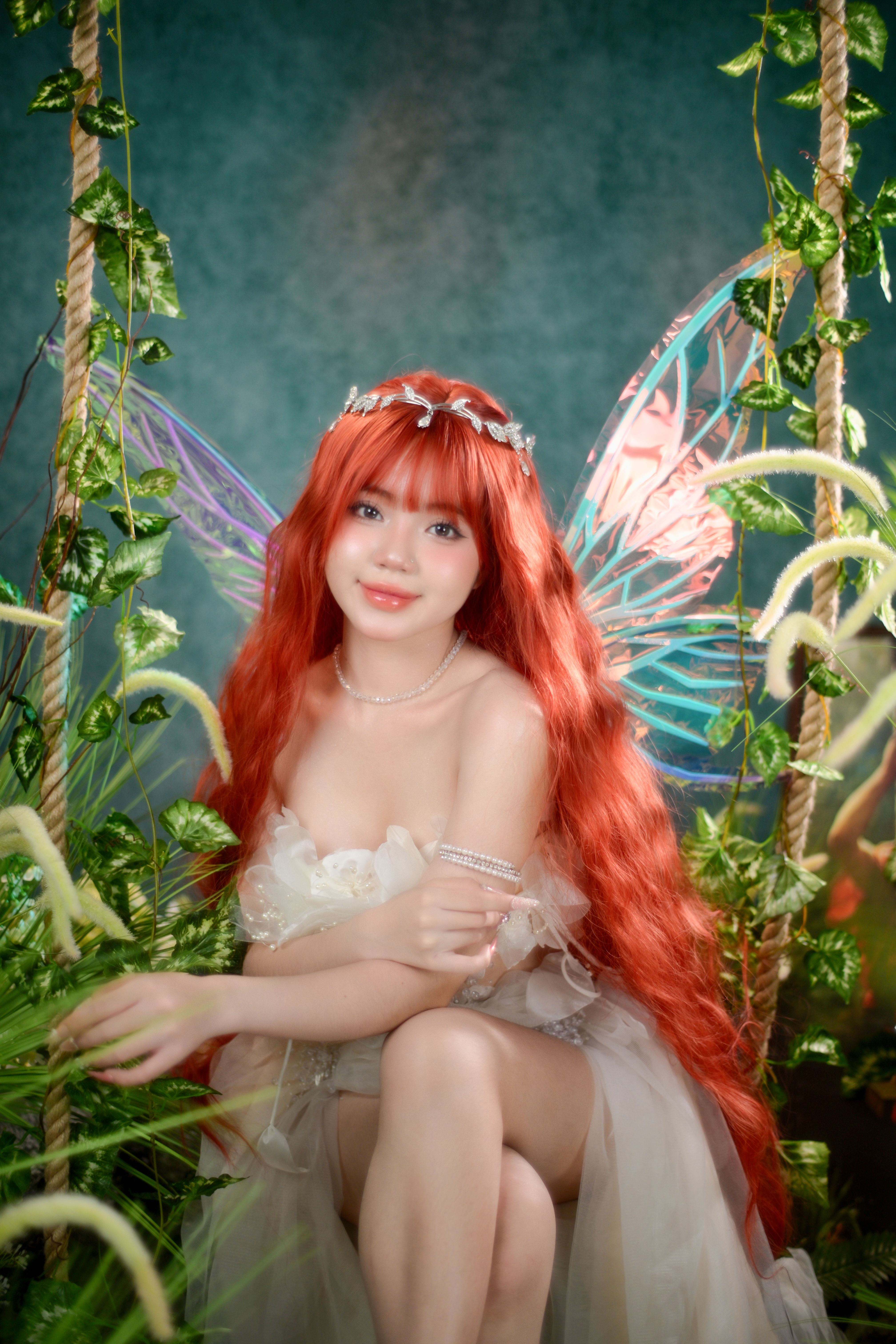 A captivating fairy with red hair sits gracefully in an enchanting garden with vibrant wings.