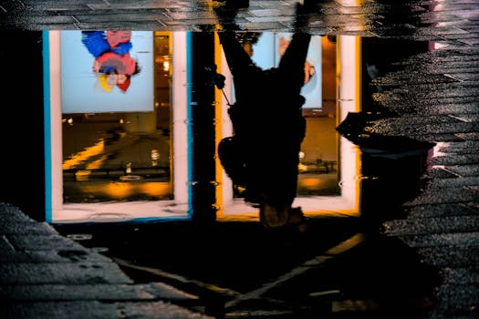 水坑中映出一个人的轮廓，捕捉着城市的灯光与纹理