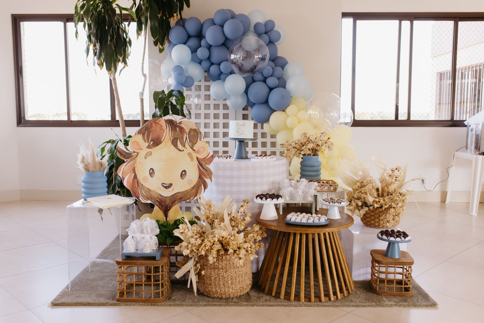 A delightful baby shower decoration featuring blue and yellow balloons, a cute lion cutout, and elegant treats.