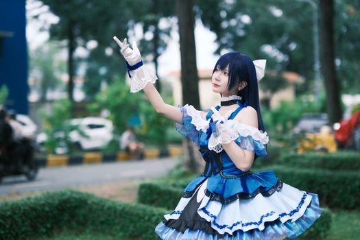 Person in intricate blue cosplay costume posing outside in a park setting.