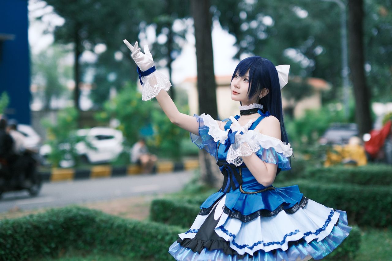 person in intricate blue cosplay costume posing outside in a park sett