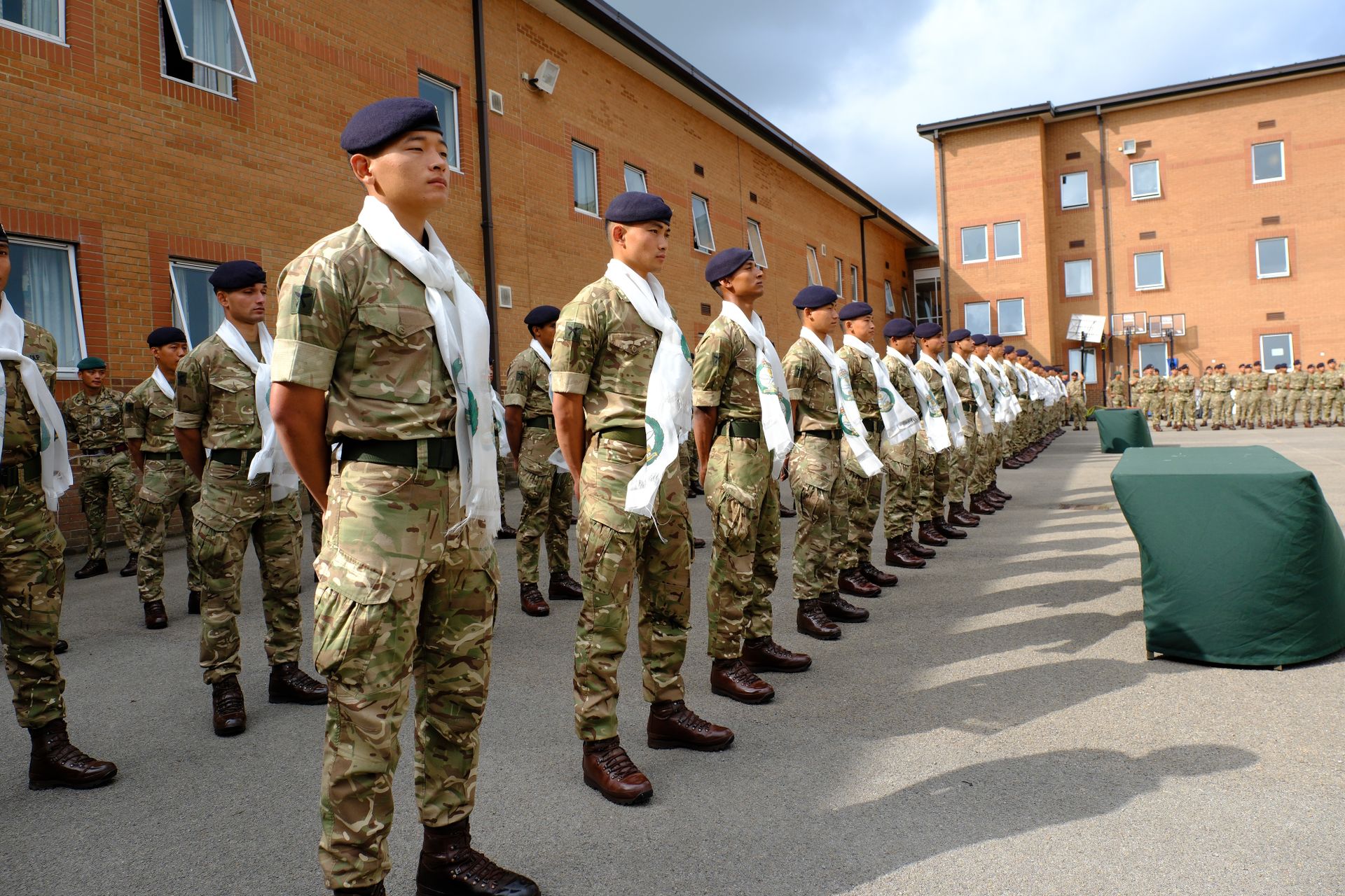 Gurkha soldiers in military uniforms stand in formation for an outdoor ceremony.