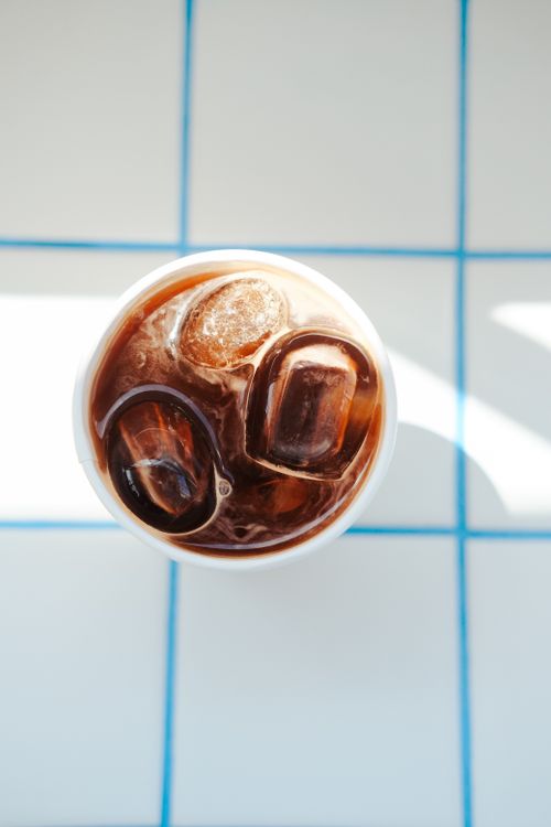 Free A top view of iced coffee on a blue-tiled surface, enhanced by natural sunlight. Stock Photo