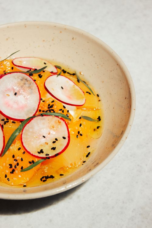 Free Refreshing citrus salad with radish and black sesame in a speckled ceramic bowl. Stock Photo
