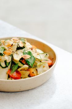 Colorful grilled vegetable salad topped with almonds served in a ceramic bowl.