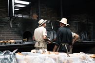 Bakers work together in a rustic setting with a wood-fired oven in Gramado, Brazil.
