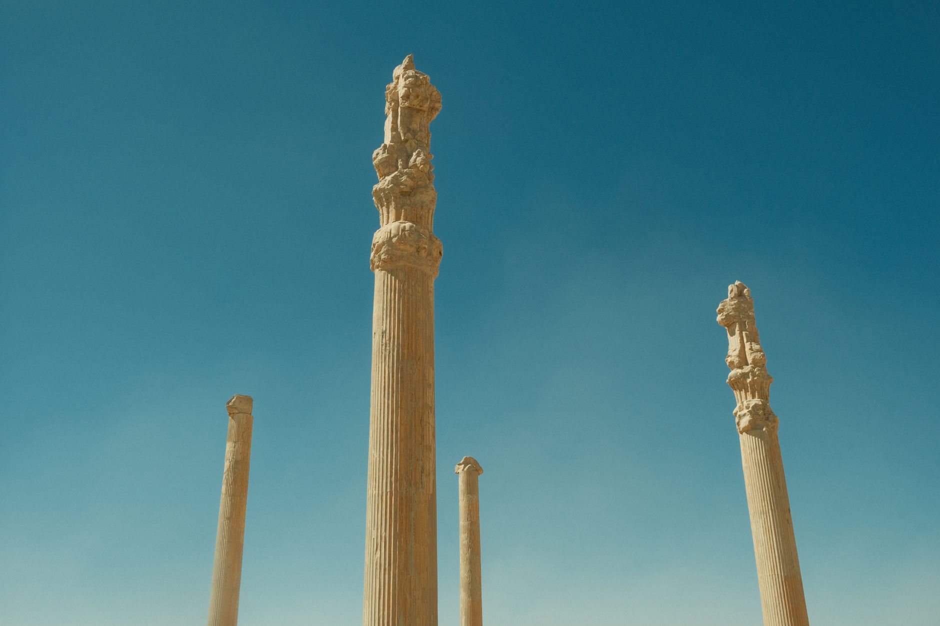 Tall stone columns of Persepolis under a clear blue sky in Marvdasht, Iran.