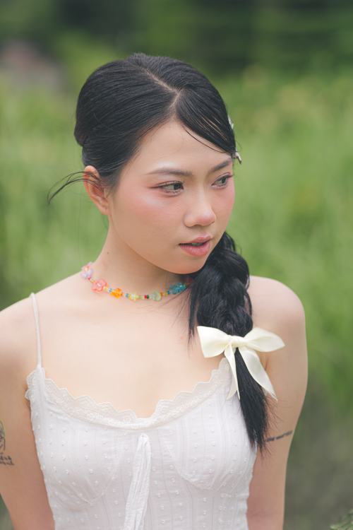 Free Portrait of a woman in a white dress and braided hair in a serene outdoor setting. Stock Photo