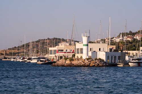 Free Charming harbor view in Foça, İzmir with a lighthouse and moored boats. Stock Photo