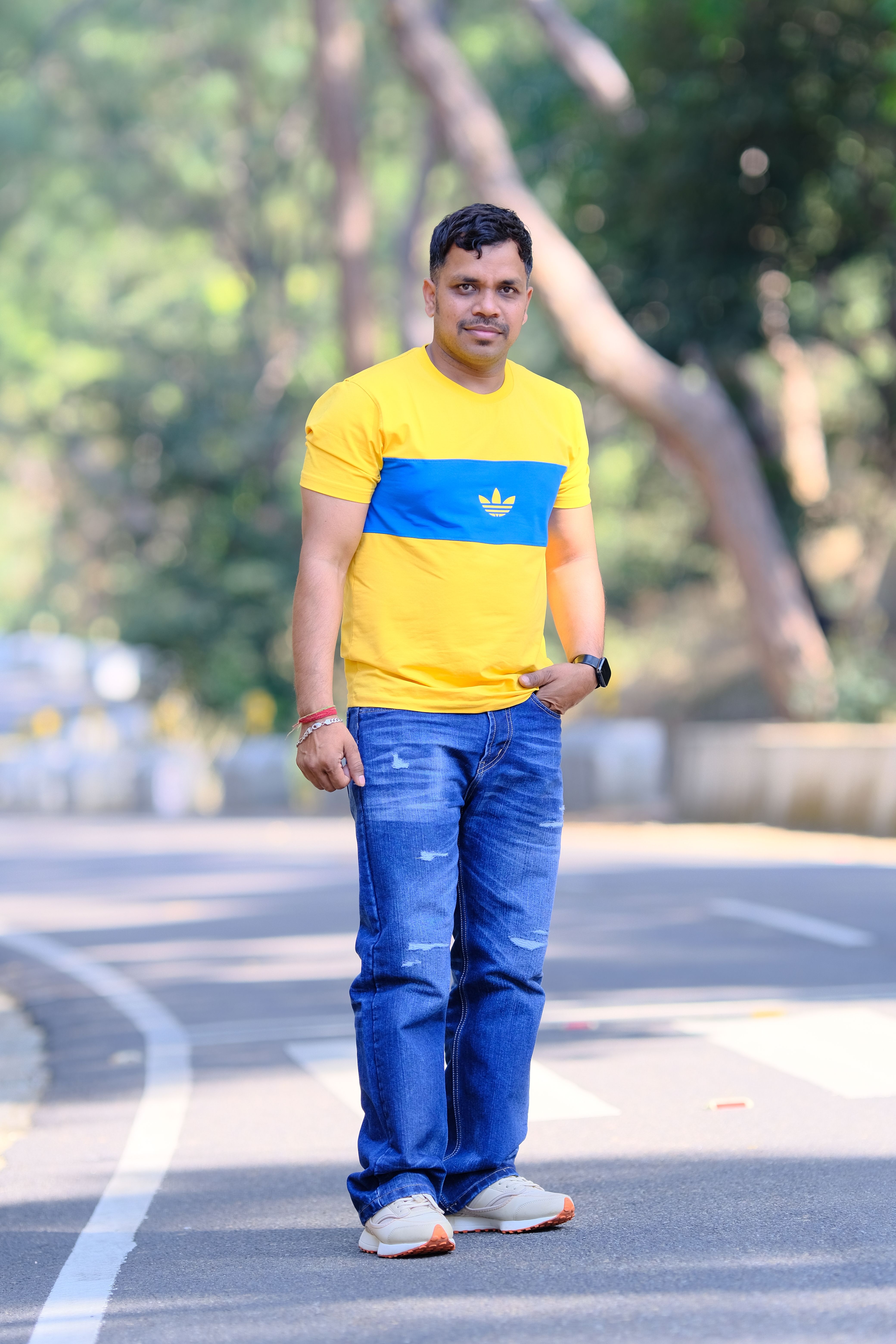 Man in casual outfit walks outdoors on a sunny day, showcasing a relaxed lifestyle.