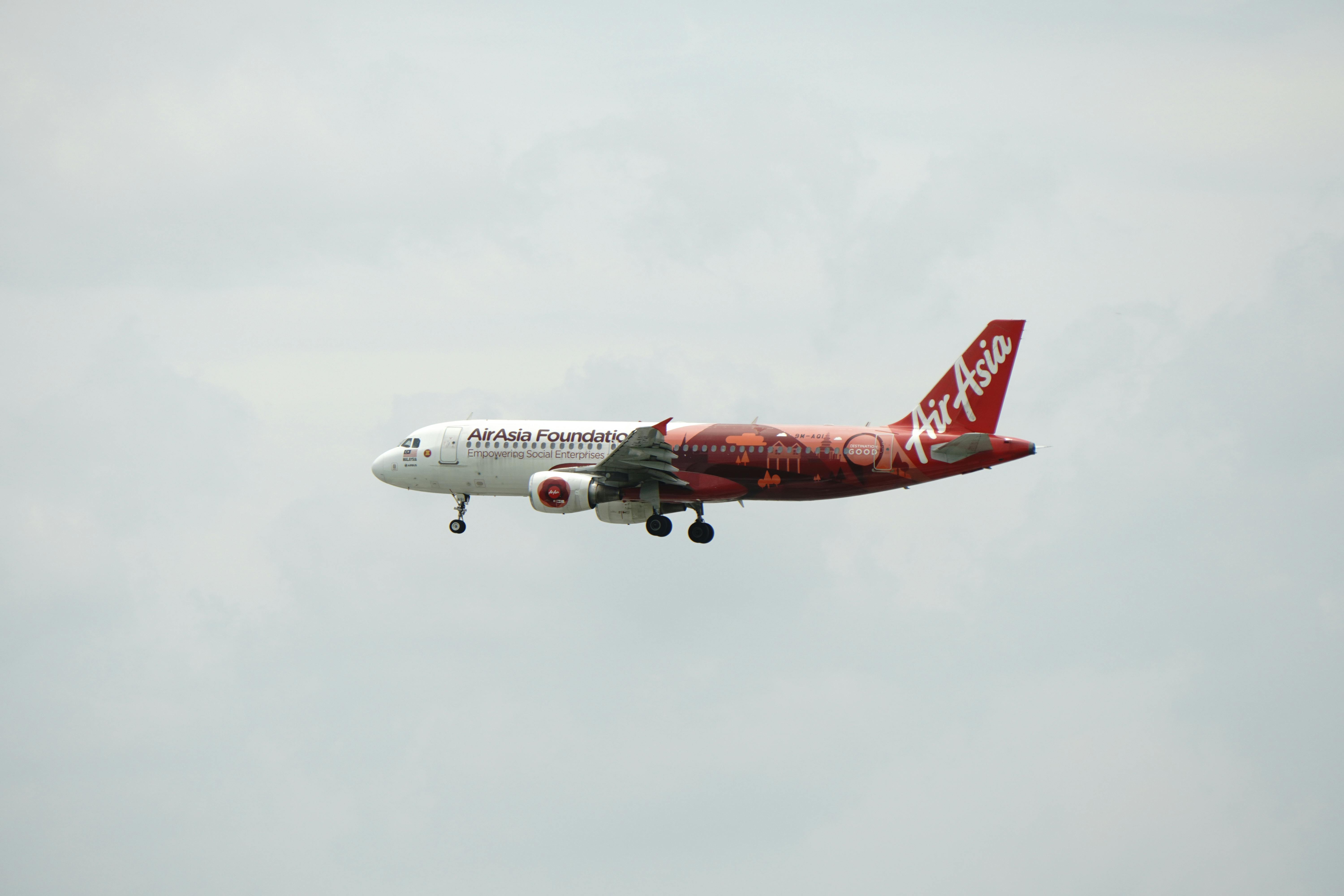 AirAsia Foundation aircraft flies against grey sky, showcasing travel and aviation.