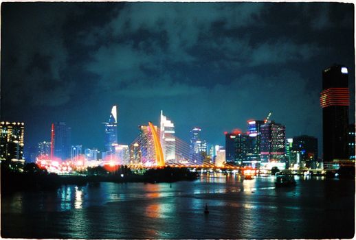 A vivid cityscape showcasing a brightly lit skyline reflecting on a river at night.