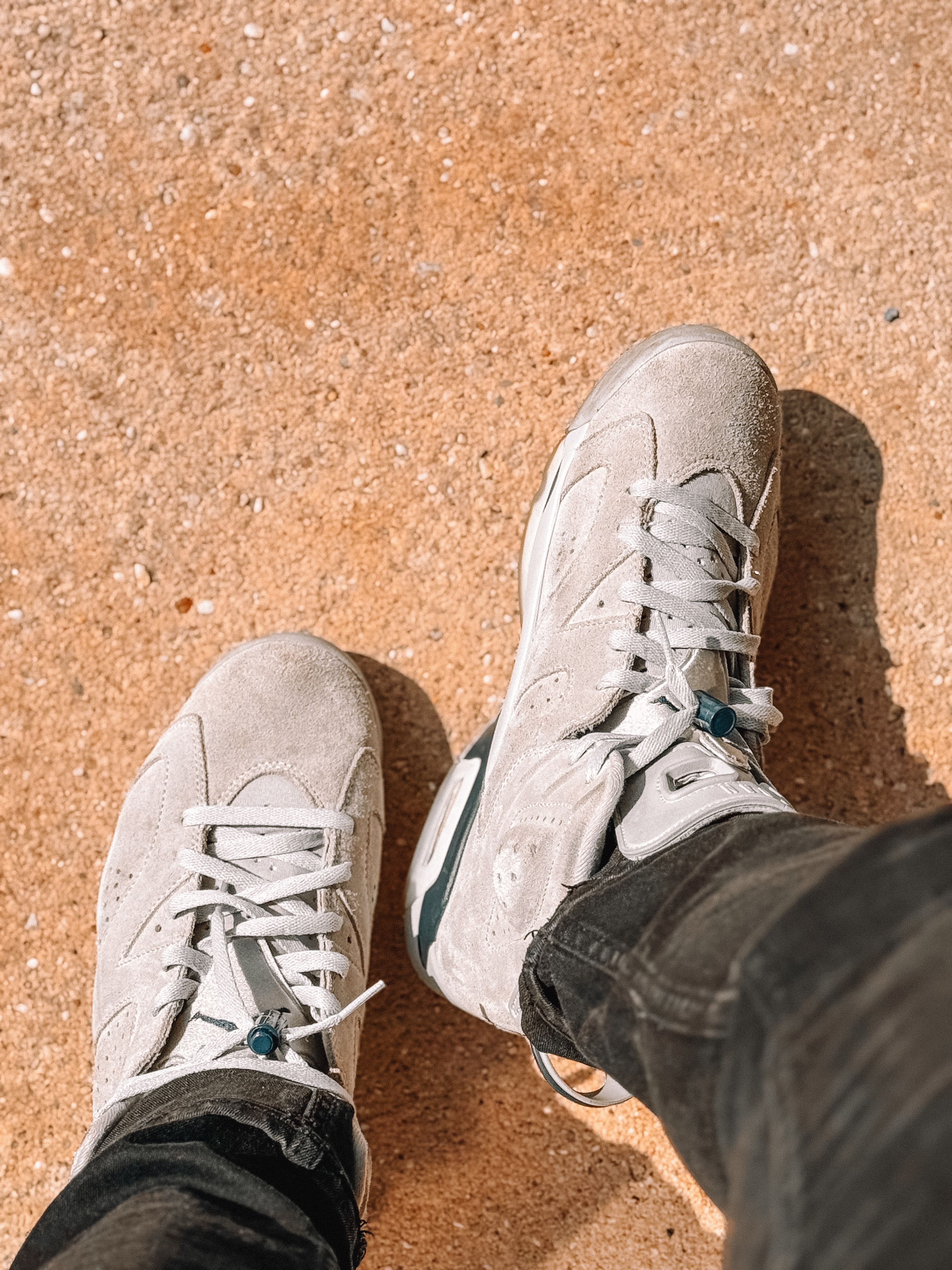 Top view of stylish sneakers worn outdoors on sandy ground highlighting modern footwear fashion.