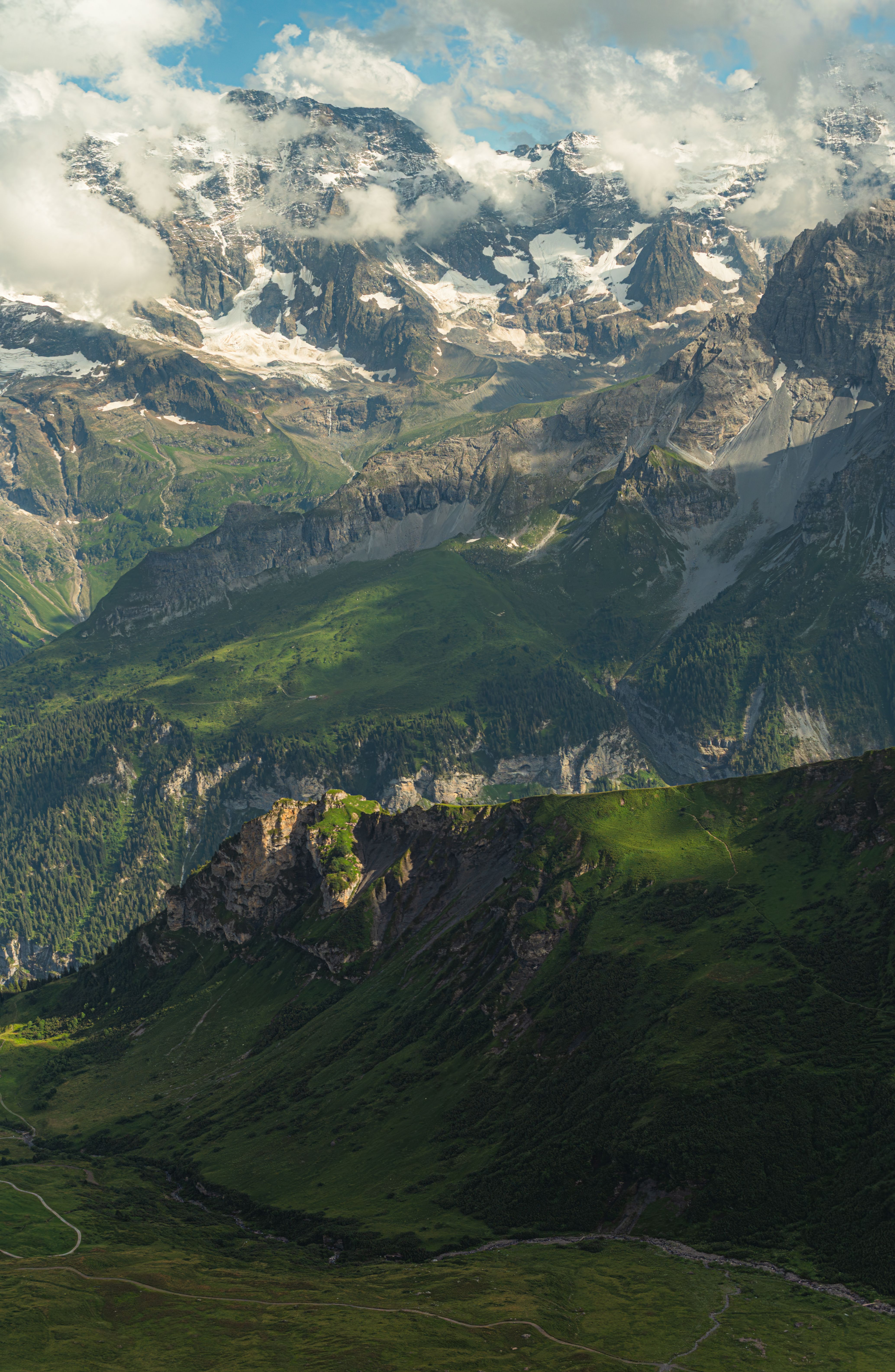 Majestic view of Swiss Alps in summer with lush green meadows and rugged peaks.