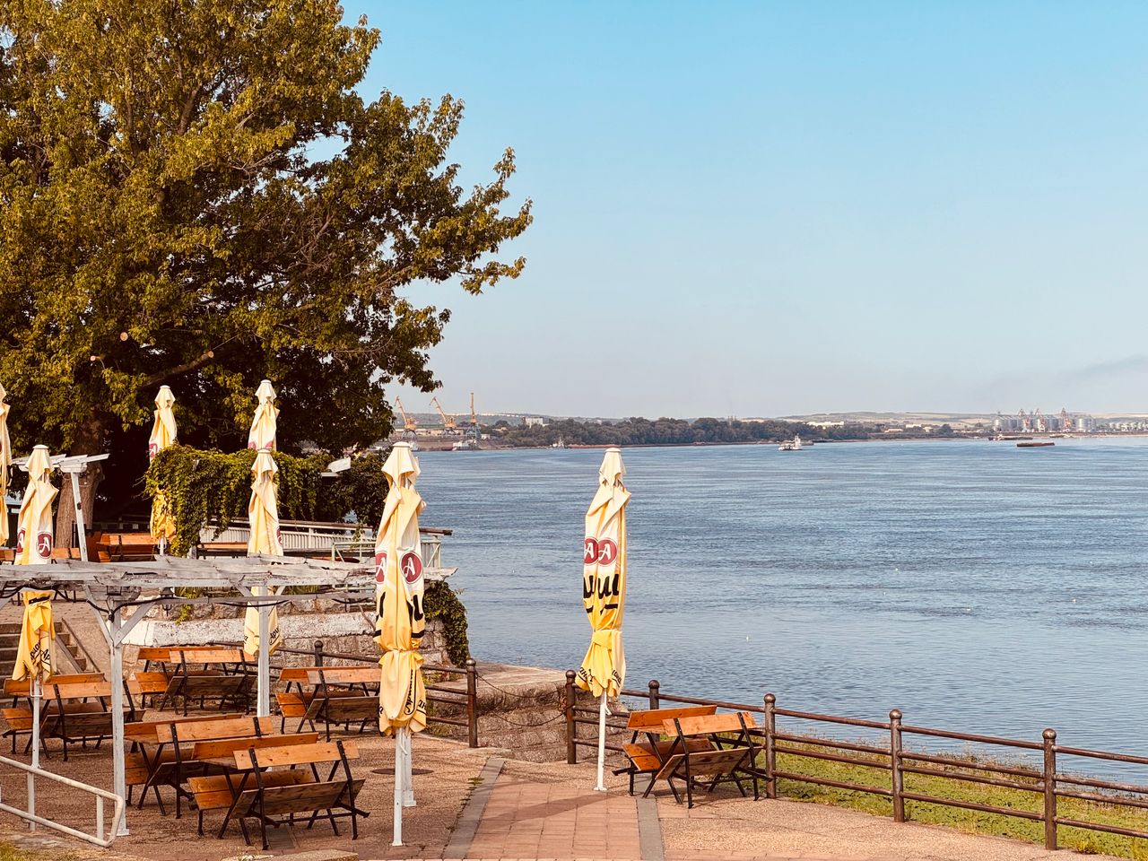 tranquil view of deserted riverside caf with closed yellow umbrellas o