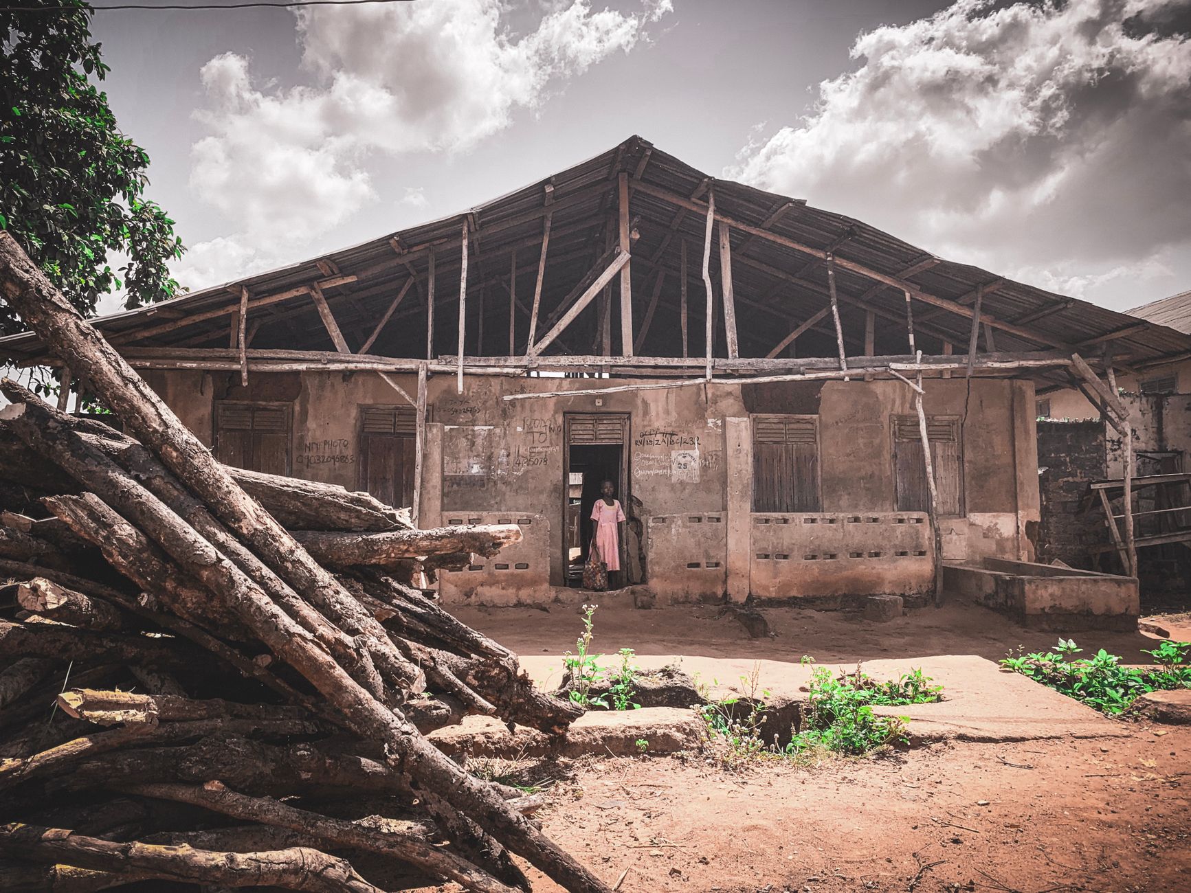 Rustic wooden house in Ilaro, Nigeria, with logs and small garden.