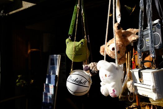 Hanging plush toys and bags in sunlight, featuring a basketball purse and teddy bears.