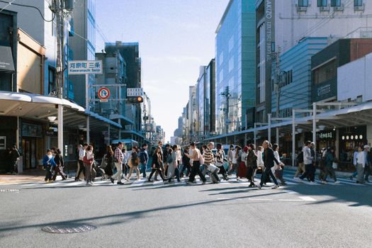 Pedestrians cross the street in the bustling Kawaramachi Sanjo area during the day.
