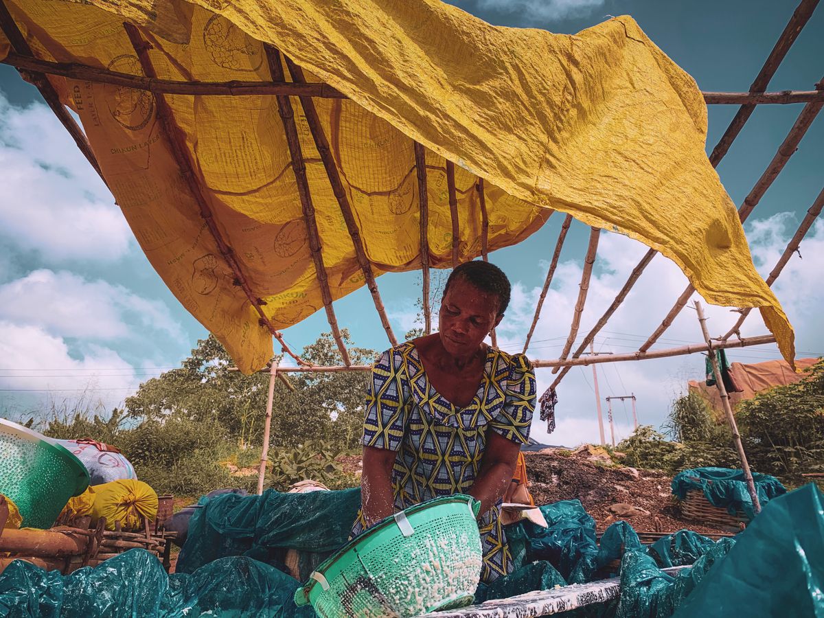 Woman working under a makeshift tent in Egbado South, Ogun State, Nigeria, a simple outdoor stand
