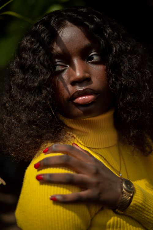 Free Elegant portrait of a woman with curly hair and red nails wearing a yellow sweater. Stock Photo