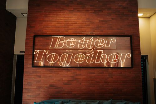 Free Neon 'Better Together' sign on brick wall adds warmth to modern interior. Stock Photo