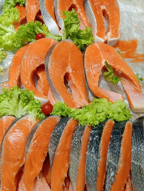 Free Freshly sliced salmon steaks displayed with lettuce and cherry tomatoes, offering a vibrant culinary presentation. Stock Photo