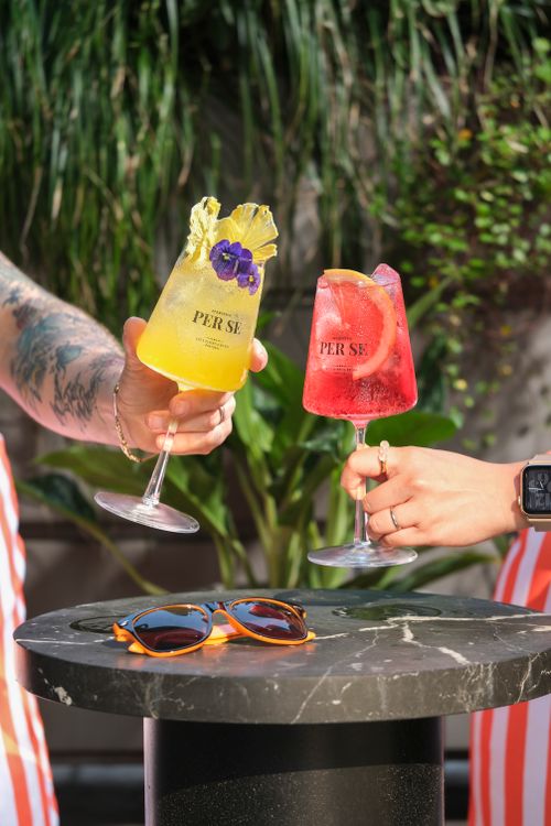 Free Vibrant cocktails raised in a toast with sunglasses on a table, set outdoors in sunny California. Stock Photo