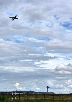 Airplane takes off under cloudy skies at Berlin airport, Germany, showcasing dynamic travel scene.