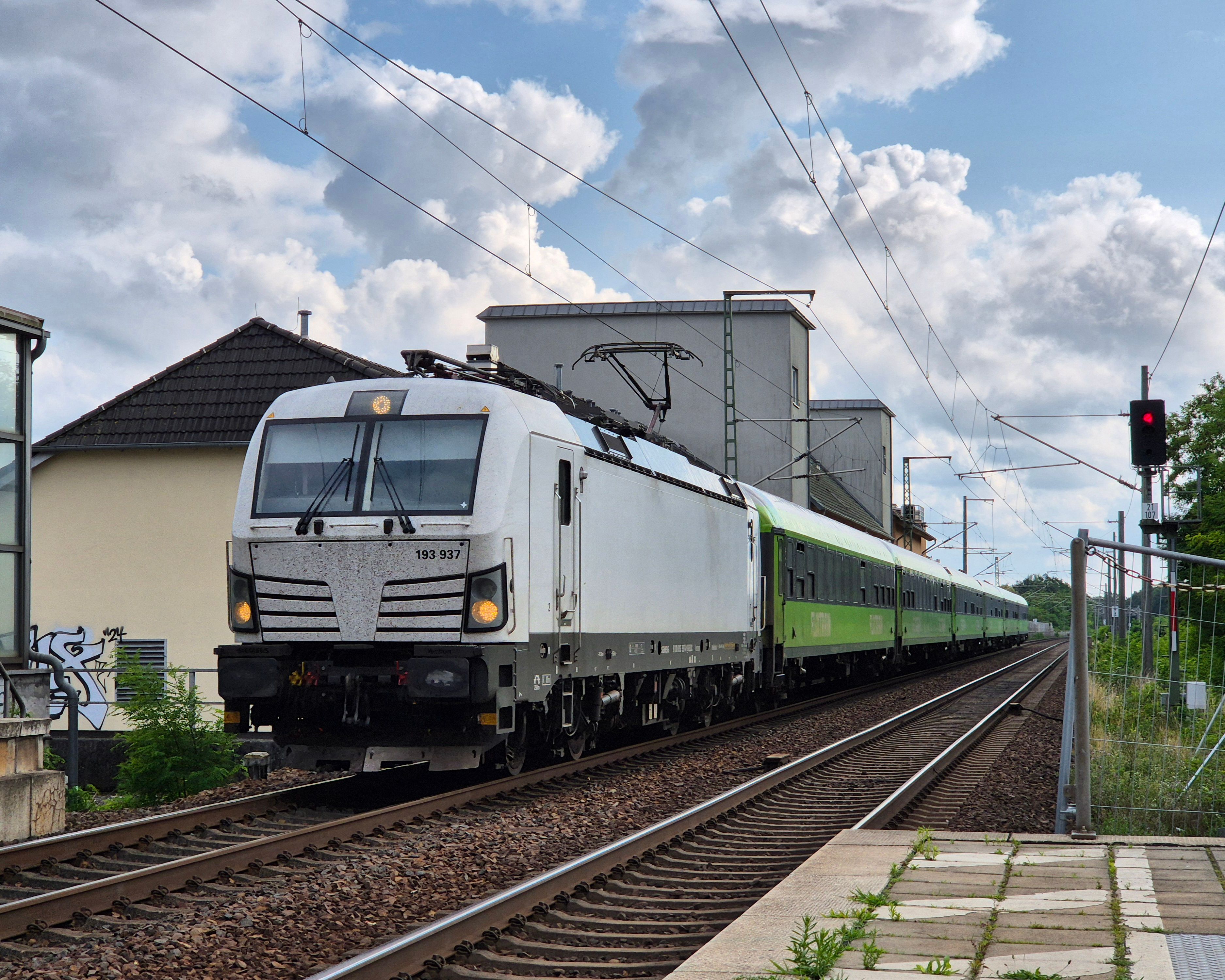 White and green train traveling through Germany on a cloudy day