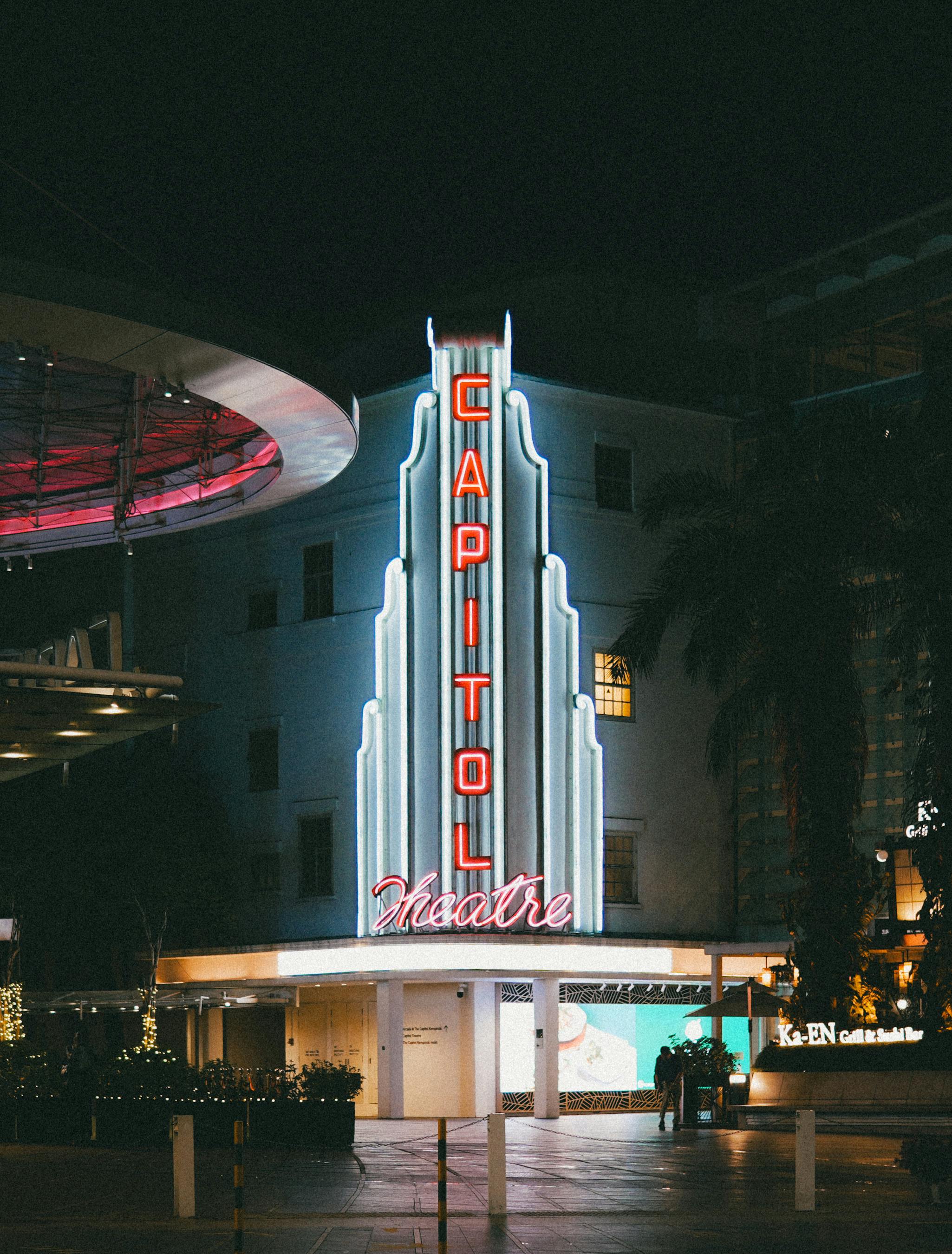 Gratis Utsikt over det opplyste skiltet til Capitol Theatre som lyser mot nattehimmelen og fremhever det urbane nattelivet. Arkivbilde