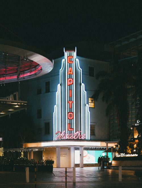 Free View of the illuminated Capitol Theatre sign glowing against the night sky, highlighting urban nightlife. Stock Photo