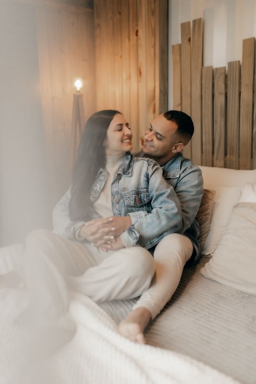 Free A couple enjoys a warm and cozy moment together sitting on a modern bed. Stock Photo