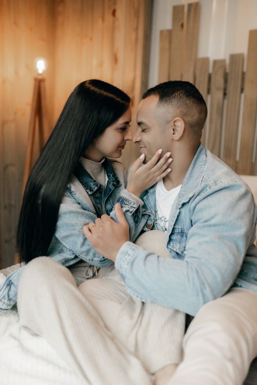 Free A young couple shares a tender moment on a cozy bed indoors, capturing warmth and affection. Stock Photo