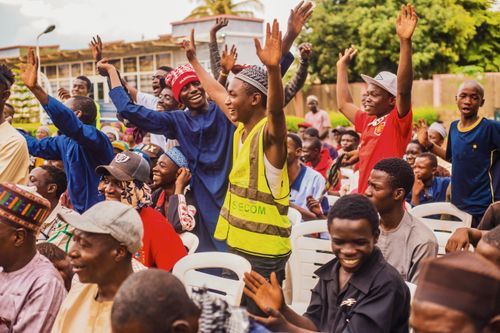 Free Lively outdoor gathering of diverse individuals in Kaduna, Nigeria, expressing joy and engagement. Stock Photo