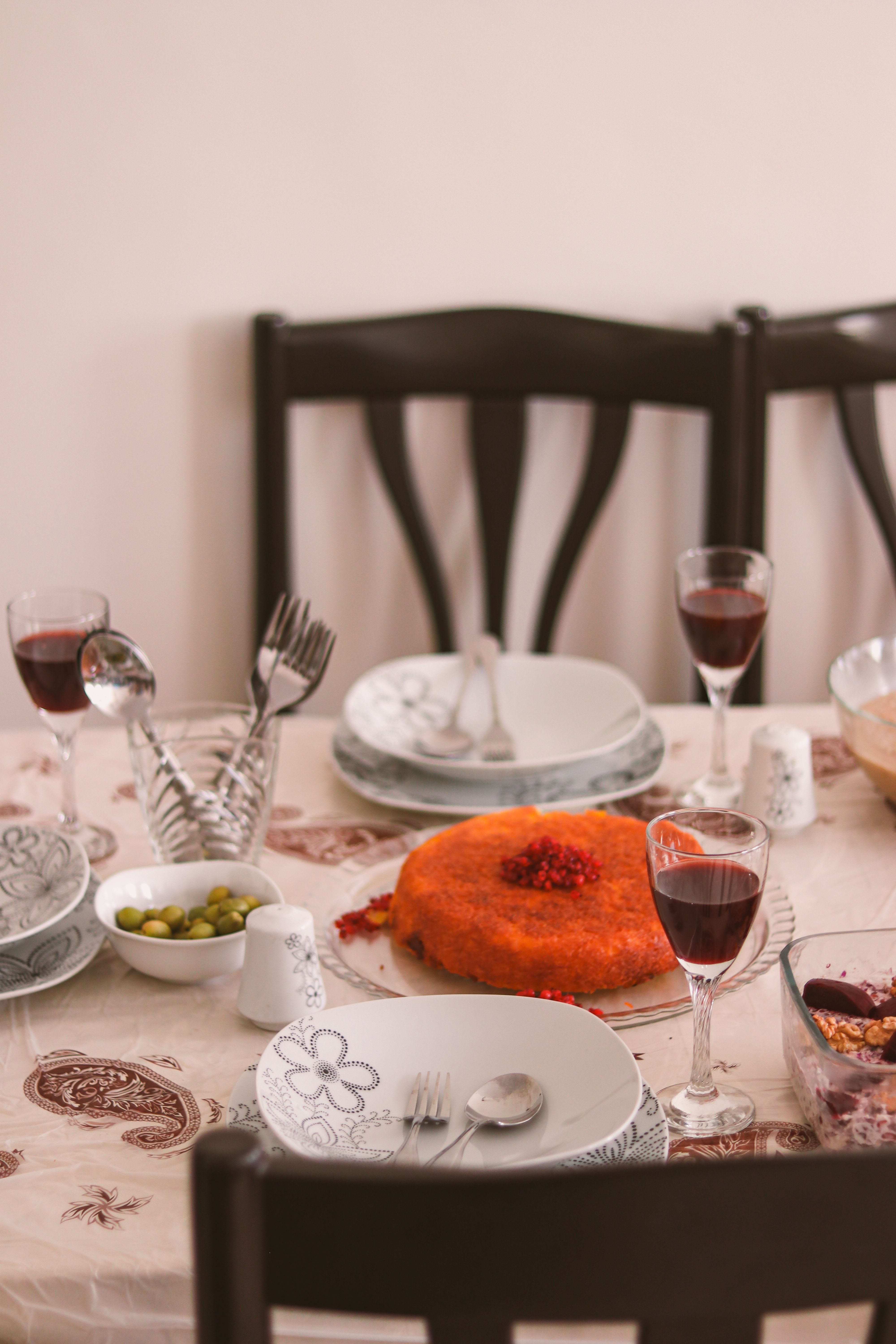 A sophisticated dining table setup featuring dessert, wine glasses, and elegant crockery.