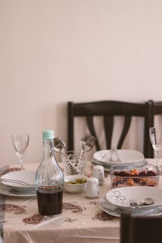 Beautifully arranged dinner table indoors with wine, dishes, and decor. Perfect for a cozy meal setting.