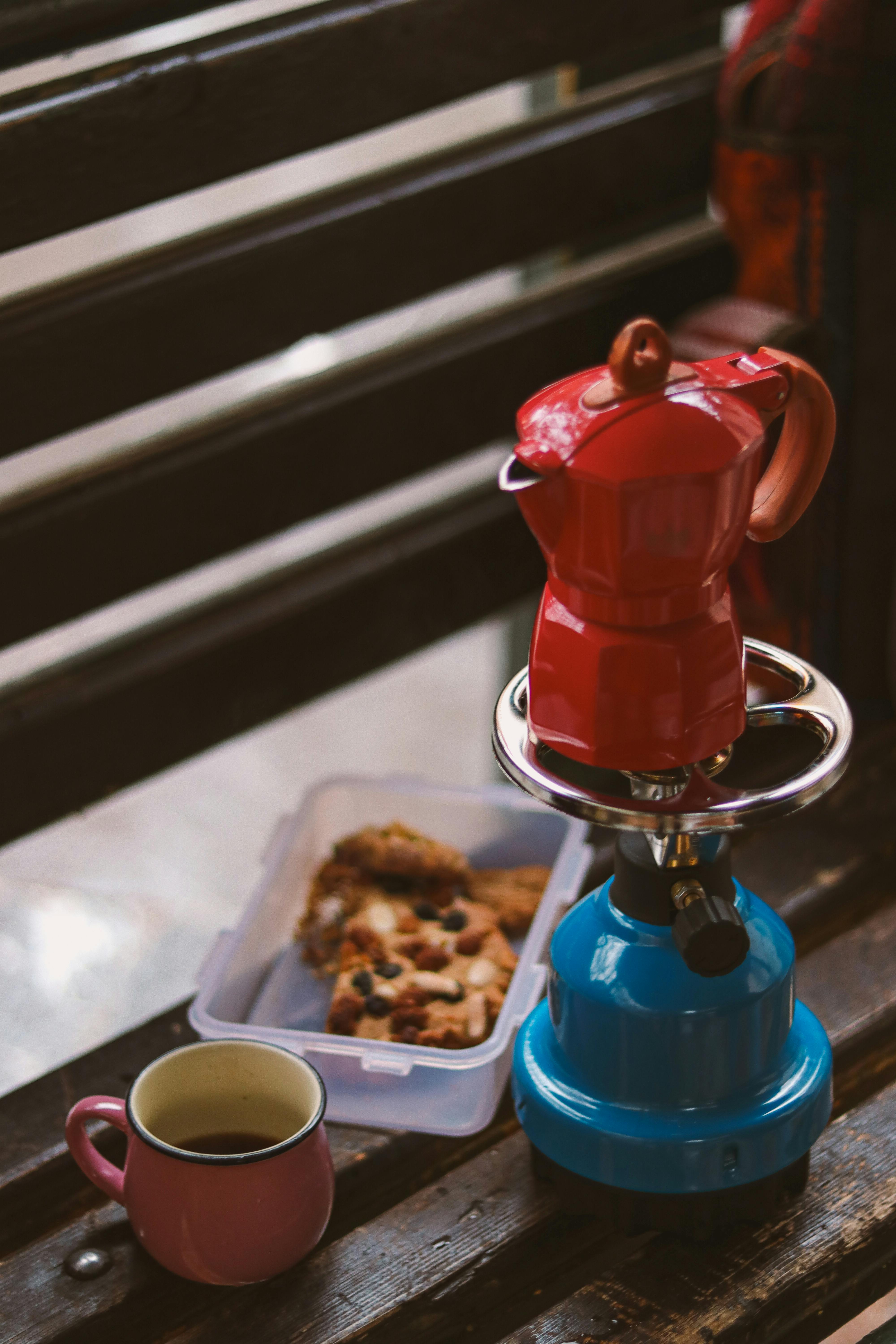 A cozy outdoor picnic setup with a stovetop coffee maker, cup, and cookies, perfect for a relaxing afternoon.