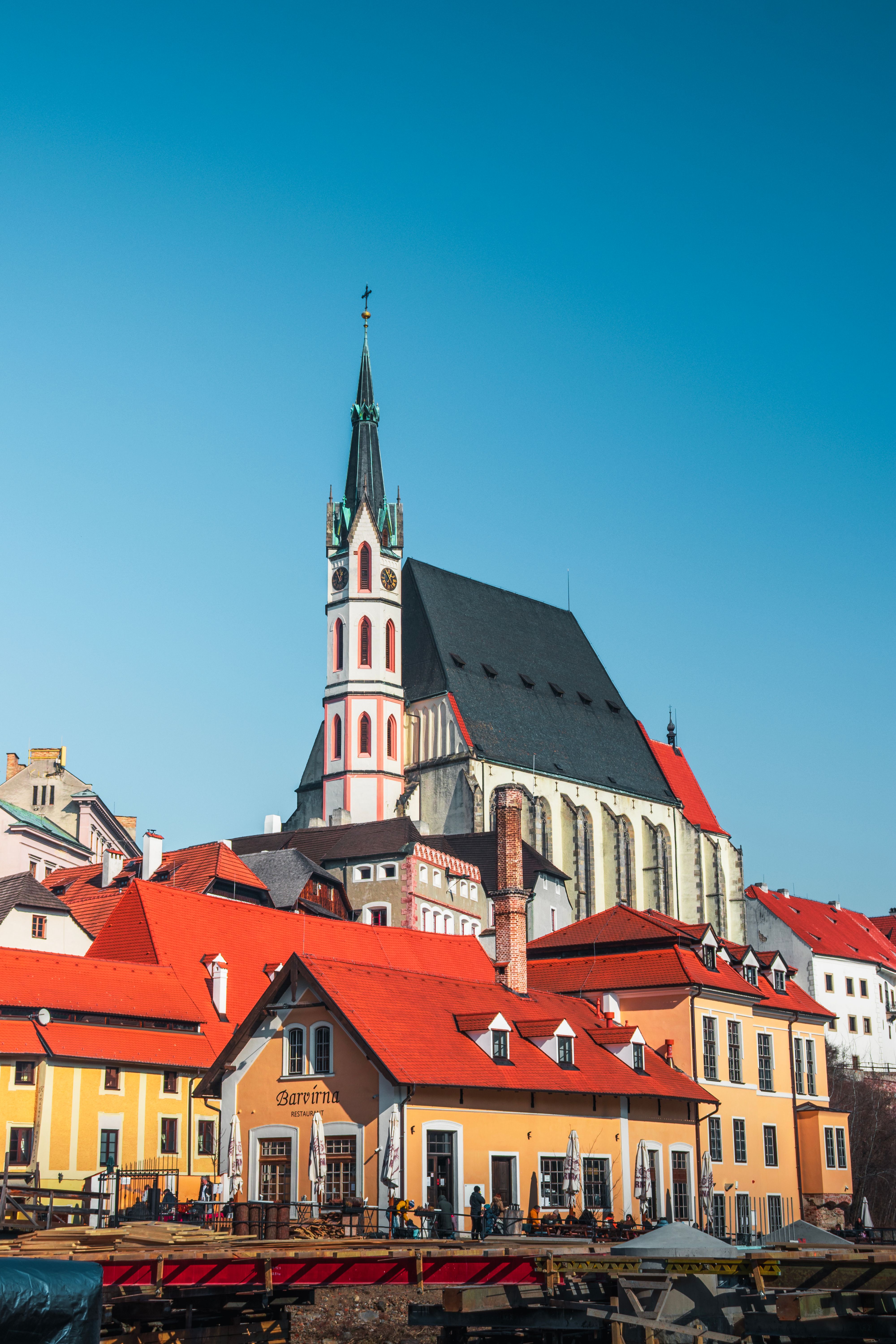 Beautiful view of Český Krumlov's iconic church and colorful buildings under a clear blue sky.