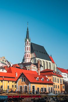 Beautiful view of Český Krumlov's iconic church and colorful buildings under a clear blue sky.