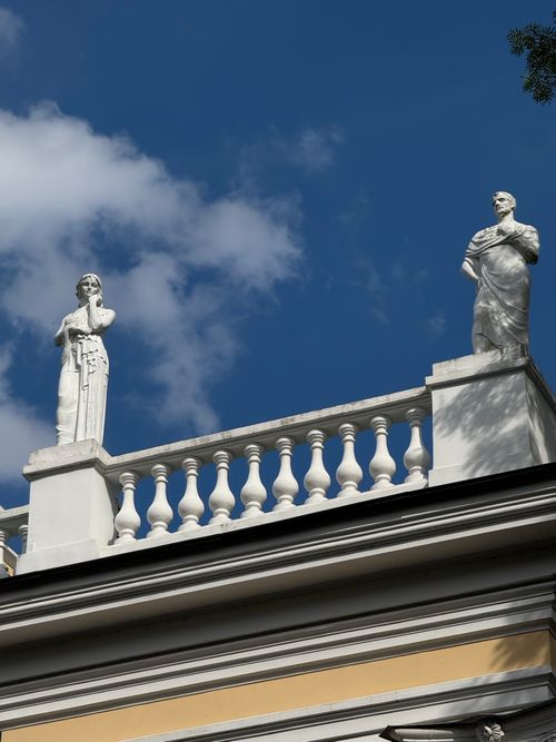 Free Elegant classical statues on a historic building facade against blue sky. Stock Photo