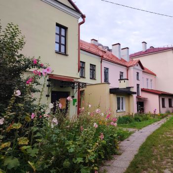 Quaint residential street with pastel houses and blooming summer garden.