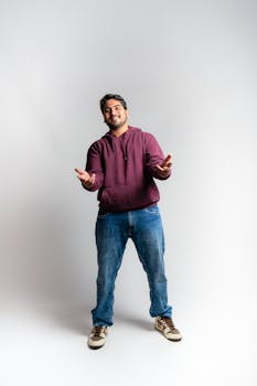 Full-length portrait of a smiling man in a casual outfit in a studio setting.
