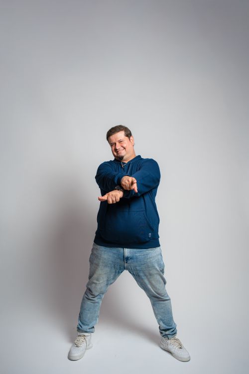 Free A joyful, casually dressed man poses playfully in a studio setting. Stock Photo