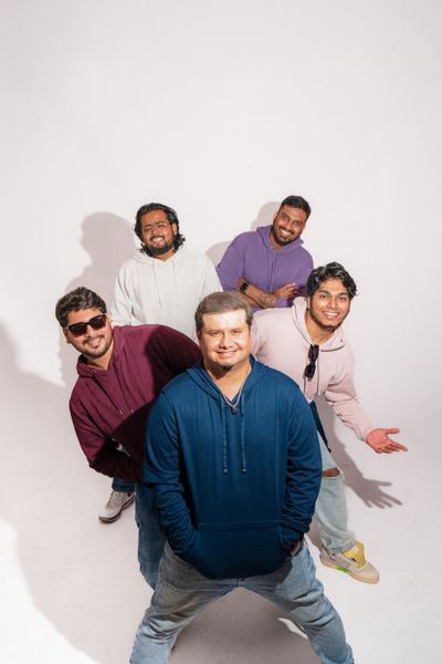 Five bandmates posing in a bright studio — Karan Mridha on Pexels