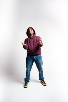 Young man in a hooded sweatshirt posing in a studio setting.