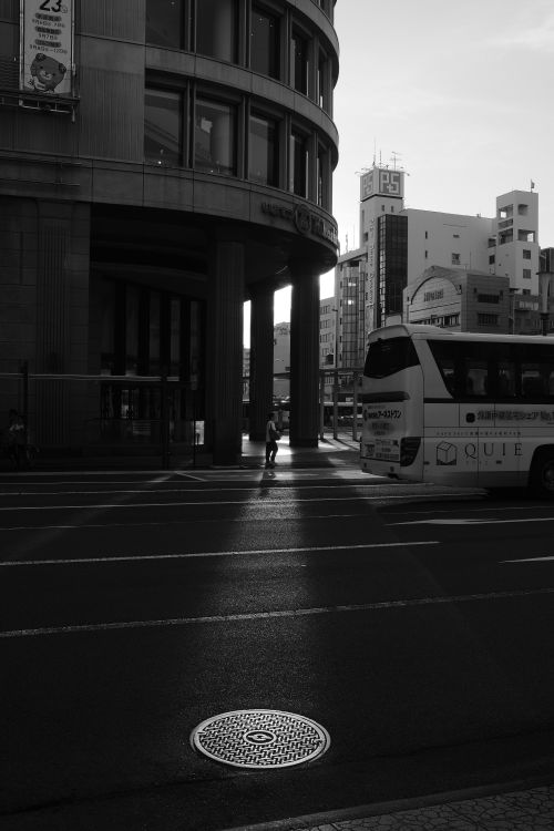 Free Atmospheric black and white photo capturing an urban street scene with a bus and architecture at dusk. Stock Photo