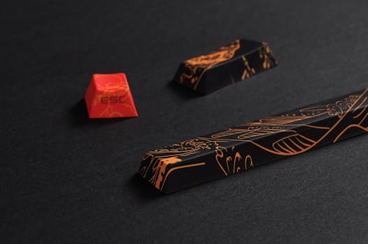 Stylish close-up of black and orange keyboard keycaps with intricate patterns, showcasing a modern artistic design.